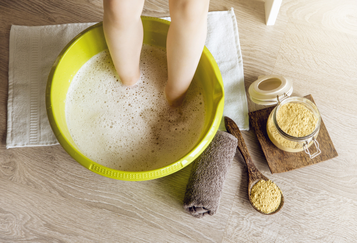 Child taking a healing warming foot bath with mustard powder, adding